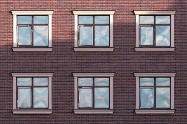 Aynı kare pencereli tuğladan bir evin ön cephesi. Evin ön cephesi. Tuğla duvar Çok katlı. Camlı pencereler. Mimaride geometri. Dış duvar.