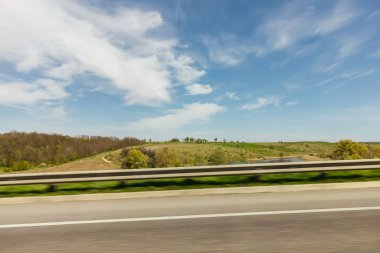 Arabanın penceresinden bak. Ukrayna 'nın manzaraları. Güneşli bir gün. Fotoğraf hızında. Mavi gökyüzünün arka planında yeşil ağaçlar. Çevreleyen manzara. 