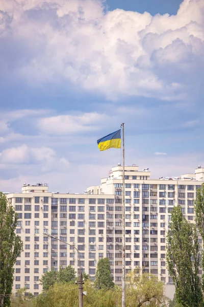 青い空と高い住宅の建物を背景に ウクライナの青黄色の国旗 ウクライナの青黄色の国旗 キエフの街並み 白い雲と青空 住宅用不動産市場 — ストック写真