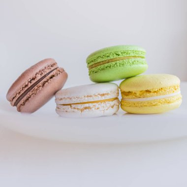 Çok renkli badem kurabiyeleri. İki yarım. Narin Fransız kurabiyeleri. Kahve tatlısı. Kurabiyeler kremaya dayanıyordu. Çıtır çıtır. İştah açıcı natürmortta renkli kurabiyeler..