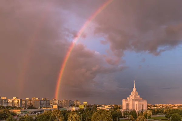 Double bright rainbow. A natural phenomenon. Heavenly landscape. Cloudy sky. Rainy weather. A white building against a cloudy sky with a rainbow. Mormon temple. Cityscape after a thunderstorm.