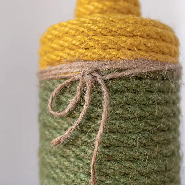 Jute product. Natural material. Textile fiber texture. Rural style. Interior decor. Craft products. Coarse thread. Decorative rope. Handicrafts as a hobby. Vase made of colored jute close-up as interior decoration.
