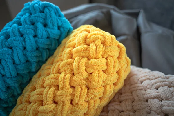 A pile of plush blankets. Knitted by hand. Warm blankets. Cozy home. Yarn with loops. Domestic life.