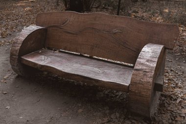 Sonbahar parkında orjinal dizaynlı ahşap bir bank. Boş bir bank. Tahta kütüklerden yapılmış koltuklar. Kırsal tarzda. Sokak mobilyası. Sonbahar Parkı.