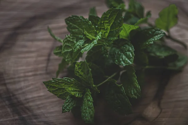 Fresh mint leaves on a wooden board. A sprig of mint. Herbal mint tea. Green color in food. Natural flavoring. Soothing drink. Ingredient for cocktails. Products for mojito. Organic food.