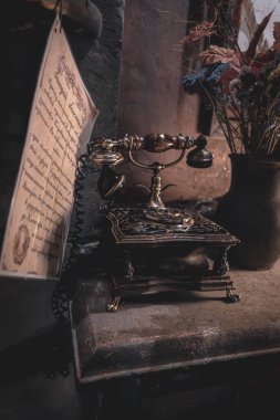 Eski bir telefon. Kablolu bağlantı. Retro tarzı. Numarayı çevir. Rakamlı disk. Mesafe iletişimi. Müze sergisi. Eski mektup. Antika ögeleri olan masa.