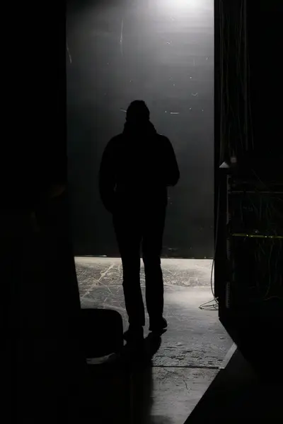 Figure of a stranger. Go away from the camera. Man in the Dark. Exit to the stage. The start of the journey. Step into the unknown. Back view of a man. Back view of a silhouette of a man in a dark corridor.