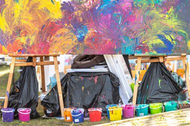 Canvas on easels. Colorful abstraction in the painting. Interior decoration. Joint creativity of people. Street art. Many different colors. Acrylic paint. Bright lifestyle. Color palette. A street painting created by many people at a charity event. clipart