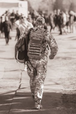 Üniformalı ve taktik sırt çantası taşıyan Ukraynalı bir asker. Ukrayna askeri. Erkek silueti. Siviller arasında ordu. Askeri gazilerin adaptasyonu. Taktik ekipman. Askeri sırt çantası. Orduda geçici hizmet. Arka plan.