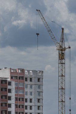 Çok katlı tuğla bir binanın yanında bir vinç. Emlak piyasası. İnşaat malzemeleri. Brick 'in evi. Modern mimari. Uyku alanı. İnşaat endüstrisi.