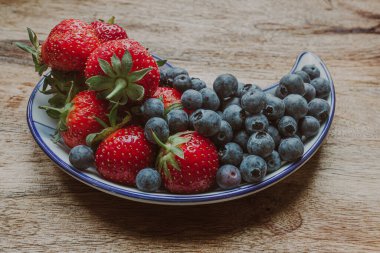 Olgun hasat. Tatlı çilek ve ekşi yabanmersini. Parlak yemek. İştah açıcı natürmort. Meyveler ve meyveler. Düşük kalorili diyet. Yaz ürünleri.