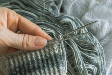 Sıcak bir fotoğrafta el yapımı kalın elbiseler ördüm. Kalın elbiseler ördüm. Kadınların hobisi. Örgü desenli. Örgü moda. El yapımı şeyler. Ev rahatlığı. Ellerinde örgü olan kız. Sonbahar ve kışın dinlenme zamanı.