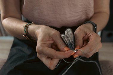Sıcak bir fotoğrafta el yapımı kalın elbiseler ördüm. Kalın elbiseler ördüm. Kadınların hobisi. Örgü desenli. Örgü moda. El yapımı şeyler. Ev rahatlığı. Ellerinde örgü olan kız. Sonbahar ve kışın dinlenme zamanı.