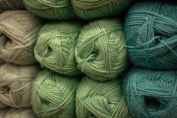 Several skeins of colored yarn at a craft store. Fluffy plush yarn in cozy colors. Crocheting and knitting. A calm and safe hobby. Yarn texture close-up. Handicraft store. A wound thread. Color gradient. Matte image. Home comfort. Seasonal leisure.