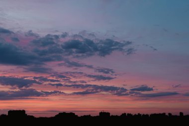 Büyük bir şehrin silueti dramatik bir günbatımı gökyüzüne karşı. Metropolis 'te akşam oldu. Evlerin taslakları. Akşam gökyüzünün parlak renkleri. Kyiv üzerinde çok renkli bulutlar. Ukrayna doğası. Şehir manzarası.