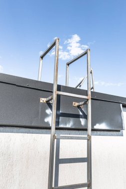 Mavi gökyüzüne giden demir merdiven. Özgürlüğü hissetmek. Merdivenlerden yukarı. Metal yapı. Çatıya erişim. Yüksel. Kariyer basamağı. Adım adım. Ayağa kalk! Soyut arkaplan. Değişikliklerin sembolü.