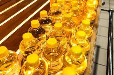 Altın renkli sebze yağıyla dolu bir raf. Ayçiçeği ya da zeytinyağı. Plastik konteynır. Mağazada rafta. Sağlıklı yiyecekler. Sağlıklı bir yaşam tarzı. İthalat ve ihracat. Ukrayna 'da ayçiçeği yağı üretimi. Yemek pişirmek için bir malzeme..