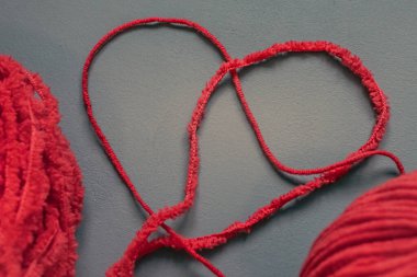 Kalp şeklinde iki kırmızı iplik var. Kırmızı iplik. Kalp şeklinde. Kırmızı ve gri. Tamirci. Örgü tarzı. Örgü ya da tığ işi. İplikten yapılmış bir kelime ya da sembol. Dikiş işi meditasyon deneyimi olarak. İplik iğrenç..