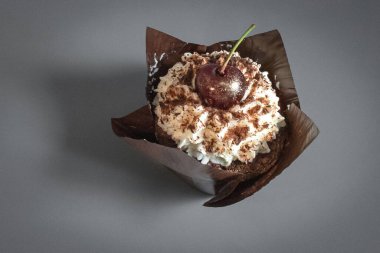 Kahverengi ambalajlı, kirazlı ve kremalı çikolatalı kek. Tatlı cazibe. Restoran geçmişi. Kafede yemek. Kahveli tatlı. Görünüş için zararlı. Kremalı kiraz. Şekerleme ürünü. Karbonhidrat diyeti.