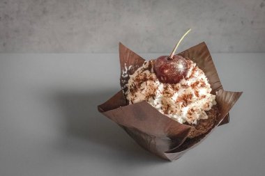 Kahverengi ambalajlı, kirazlı ve kremalı çikolatalı kek. Tatlı cazibe. Restoran geçmişi. Kafede yemek. Kahveli tatlı. Görünüş için zararlı. Kremalı kiraz. Şekerleme ürünü. Karbonhidrat diyeti.