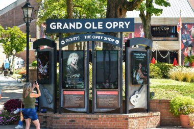 Nashville, TN, ABD 22 Eylül 2019 Turistler, country müzik ve tarihini onurlandırmaya adanmış dünyaca ünlü bir konser salonu olan Grand Ole Opry House 'un girişinde fotoğraf çekiyorlar. Bir reklam panosu, Dolly Parton 'ın yakında vereceği konseri gösteriyor..