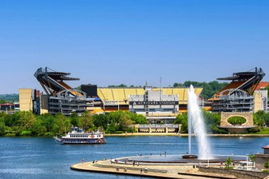 Pittsburgh, PA, USA- 21 Mayıs 2023 Acrisure Steelers 'ın evi Acrisure Stadyumu ile Allegheny Nehri' ndeki Point State Park Parkı Pınarı 'nın arasından geçen bir nehir gemisi..