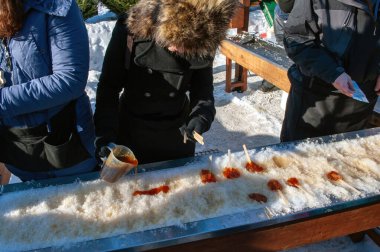 Ottawa Winterlude 'da karlara akçaağaç şekeri dökülüyor. Mevsimlik ziyafet Doğu Kanada ve New England 'ın bazı bölgelerinde bir gelenektir..