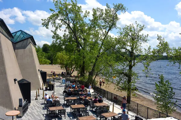 Ottawa, Kanada 28 Haziran 2025: İnsanlar Ottawa 'nın batı ucundaki Ottawa Nehri üzerindeki Westboro Sahili' nin tadını çıkarıyorlar. Plaj, restoranı, kahvesi, voleybol sahaları ve banyosu olan sıfır karbonlu bir pavyon da dahil olmak üzere son zamanlarda yeniden açıldı.