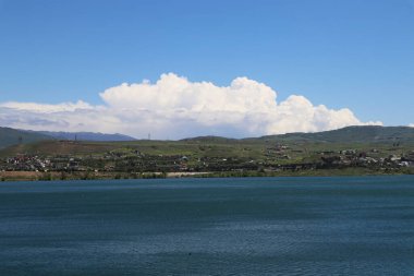 Mavi göl, tepeler, mavi gökyüzü ve bulutlar 