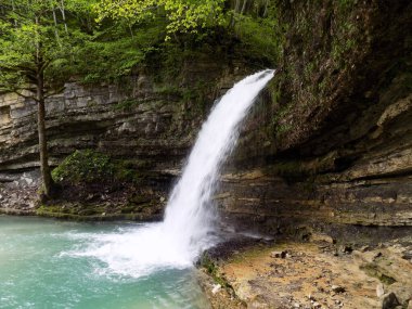 Bir şelale ve ormanda küçük yeşil bir göl. Gürcistan 'ın Kincha köyünde yer alan Lomina Gölü.           