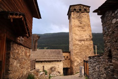 Akşamları dağların arka planına karşı Svan kulesi ve ev. Mestia, Georgia 