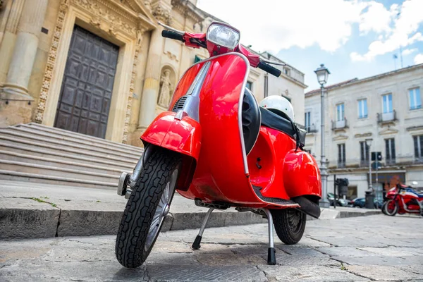 stock image red scooter parked on a stone road