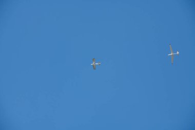 Mavi gökyüzüne karşı planörü uygun yüksekliğe taşıyan küçük bir uçak.