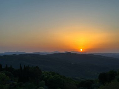 Tuscany 'deki dağ tepelerinde muhteşem bir gün batımı.