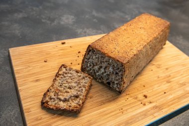 Freshly baked whole grain bread loaf with slices on wooden board. Home baking, healthy eating and artisan food concept clipart