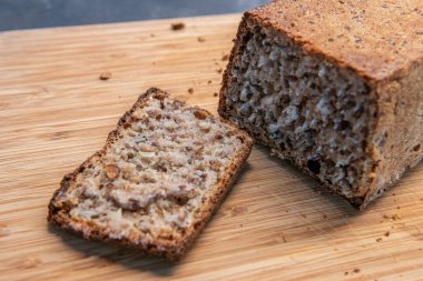 Freshly baked whole grain bread loaf with slices on wooden board. Home baking, healthy eating and artisan food concept clipart