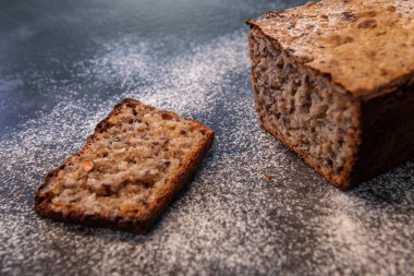 Un kaplı bir tezgahta dilimlenmiş taze fırınlanmış tam tahıllı ekmek. Ev yapımı, sağlıklı beslenme ve zanaatkar yemek kavramı.