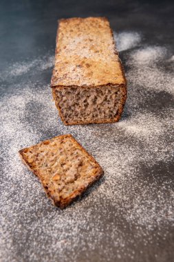 Freshly baked loaf of whole grain bread with slices on a floured countertop. Concept of home baking, healthy eating and artisan food clipart