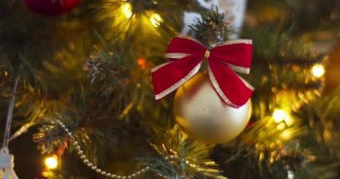 Noel ağacı süs ve oyuncaklarla dolu. Süslü bir Noel ağacına asılı kırmızı kurdeleli altın mücevher manzarası. Mutlu Noeller ve mutlu tatiller, yeni yıl atmosferi