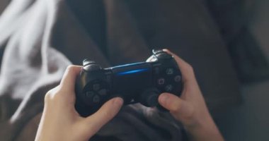 PlayStation 4 çift şok kontrolörüyle oyun oynayan genç kız.