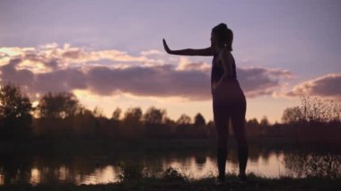 Sabahları jimnastik ya da yoga yapan genç bir kızın silueti. Spor salonu dışında beden eğitimi, dışarıda spor..