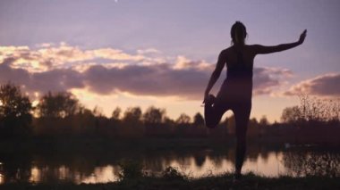 Sabahları jimnastik ya da yoga yapan genç bir kızın silueti. Spor salonu dışında beden eğitimi, dışarıda spor..