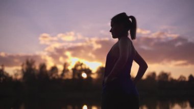 Sabahları jimnastik yapan genç bir kızın silueti. Spor salonu dışında beden eğitimi, dışarıda spor..