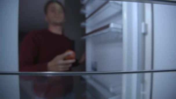 冷蔵庫を開ける男 アップルを閉じてください 冷蔵庫の中からの眺め — ストック動画