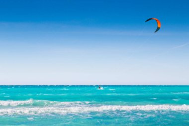 Uçurtma sörfü, açık gökyüzünün altında mavi denizde sörf yapan adam.