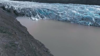 Beyaz buzulun tepeleri üzerinde siyah kül ve göl manzarası. İzlanda 'daki milli parktaki manzara buzdağı.