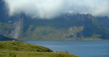 Lofoten, Reine Nordic Fjords ve Mavi Göl 'ün statik çekimi. Mavi gökyüzü ve yavaş hareket eden bulutlarla yaz.