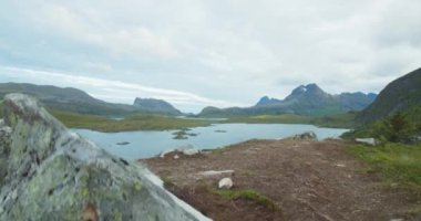 Göl ve dağlar manzaralı. Lofoten Adaları, Norveç fiyortlarının güzel doğası. Ön planda kayalık arazi