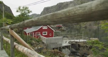 Geleneksel Norveç kırmızı kulübesi dağ manzarasında bir gölün yanında. Küçük bir balıkçı limanı. Tatiller ve eğlence konsepti.