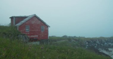 Sabahın erken saatlerinde sisli bir günde. Sisin içinde geleneksel Norveç kırmızı kulübesinden bir kare. Dağ bölgesi, Lofoten, Norveç.